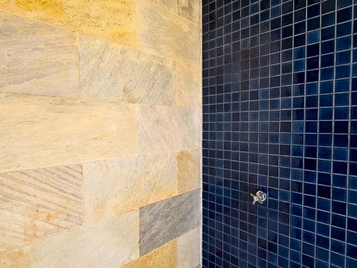 Acabamento de banheiro de alto padrão com revestimento em mosaico e pedra natural, obra executada pela JETA Engenharia.